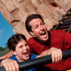 A father and son enjoy a thrill ride at a Disney Park.